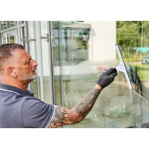 Mann reinigt Fenster mit Unger Fensterwischer aus dem 5-teiligen Glasreinigungsset. Für streifenfreie Sauberkeit.