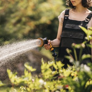 Frau bewässert Garten mit Fiskars Sprühpistole Multi mit 5 Funktionen.