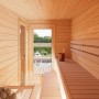 Innenansicht: Palmako Sauna Sanna Slide Plus aus naturbelassenem Fichtenholz mit Bänken und Ofen.