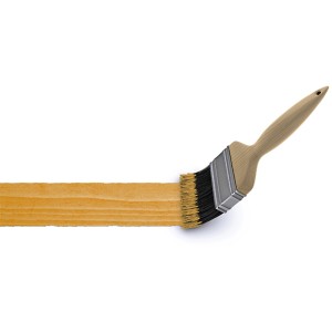 Pinsel mit Holzgriff streicht eine Fläche in Eiche hell.