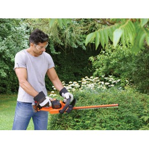 Mann schneidet Hecke mit Black+Decker Akku-Heckenschere GTC18504PC. 18V Akku-Heckenschere im Einsatz.