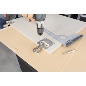 wolfcraft Reparaturset für Topfscharniere: Person bohrt Scharnier mit Montageplatte an Tür.