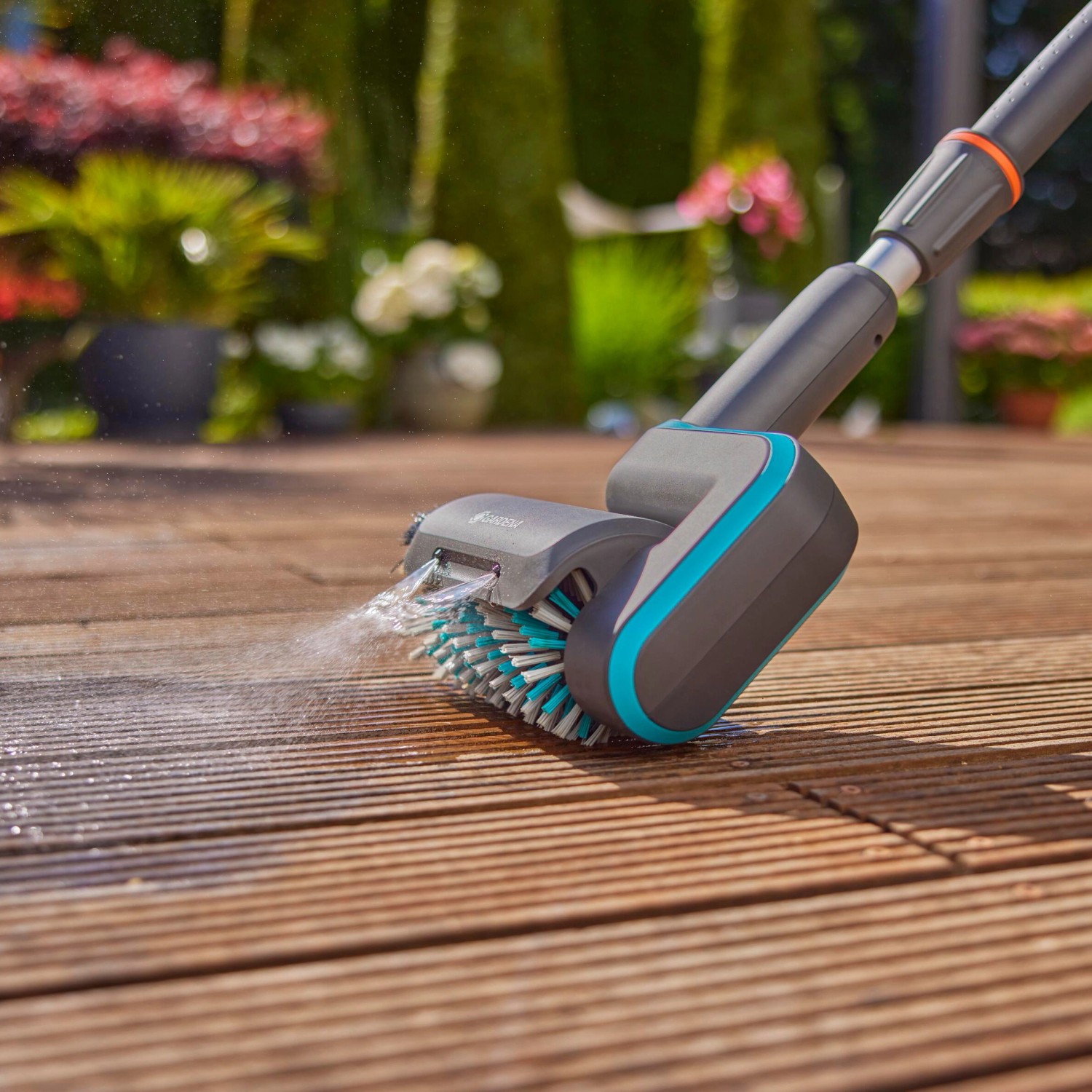 Gardena AquaBrush Universal Akku-Multi-Reiniger in Aktion auf Holzterrasse.