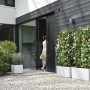 Weißer Elho Vivo Next Pflanztopf 40 cm mit Rollen im Garten.