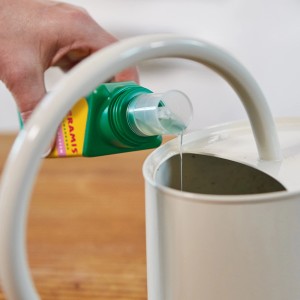 Seramis Vitalnahrung für Orchideen wird in eine Gießkanne gegossen.