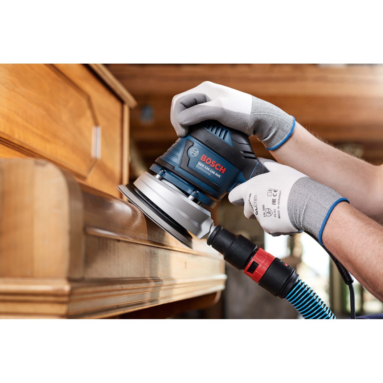 Bosch Exzenterschleifer beim Schleifen von Holzmöbeln mit Netzschleifscheibe. Staubabsaugung angeschlossen.