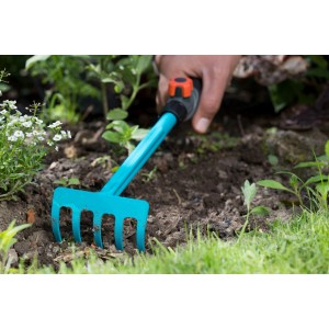 Gardena Combisystem Kleingeräte Set: Hand mit Rechen im Gartenboden.