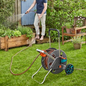 Gardena CleverRoll L Easy Schlauchwagen mit Person beim Bewässern im Garten.