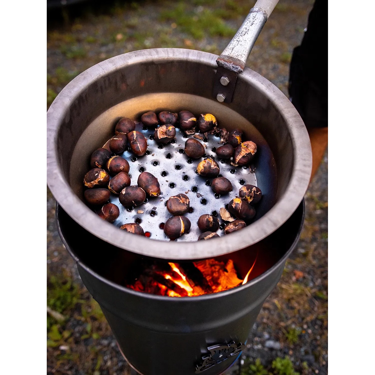 GuC Maronipfanne aus Stahl mit Maronen über offenem Feuer. Grillutensil für leckere Kastanien.