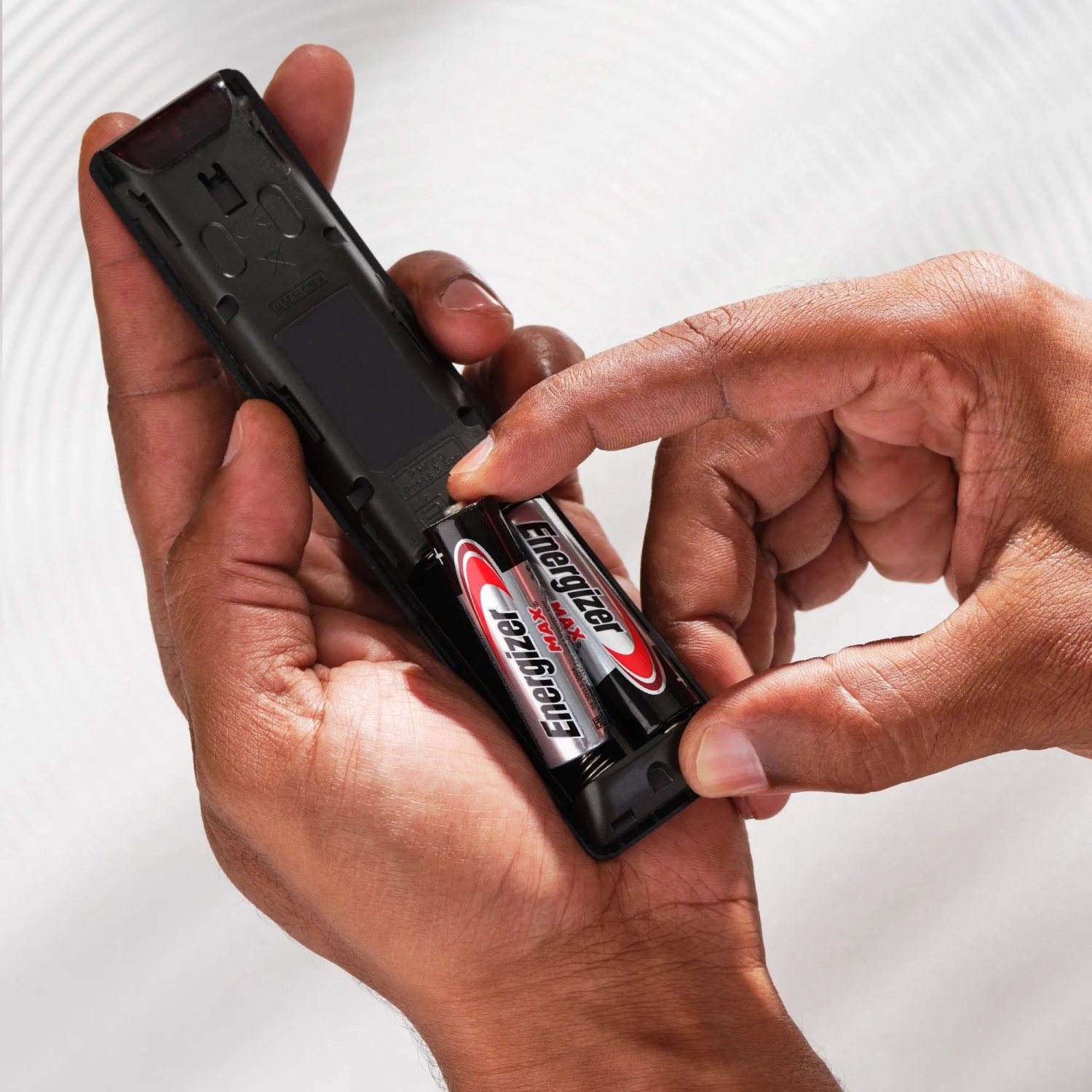 Einsetzen von Energizer AA Batterien in eine Fernbedienung.