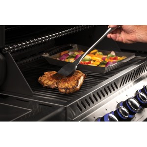 Napoleon Grillbesteck: Wender bestreicht Steak auf Grill, Gemüsepfanne im Hintergrund.