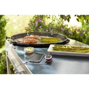 Weber iGrill Mini Bluetooth-Thermometer mit Messfühler beim Grillen von Fleisch und Spargel.