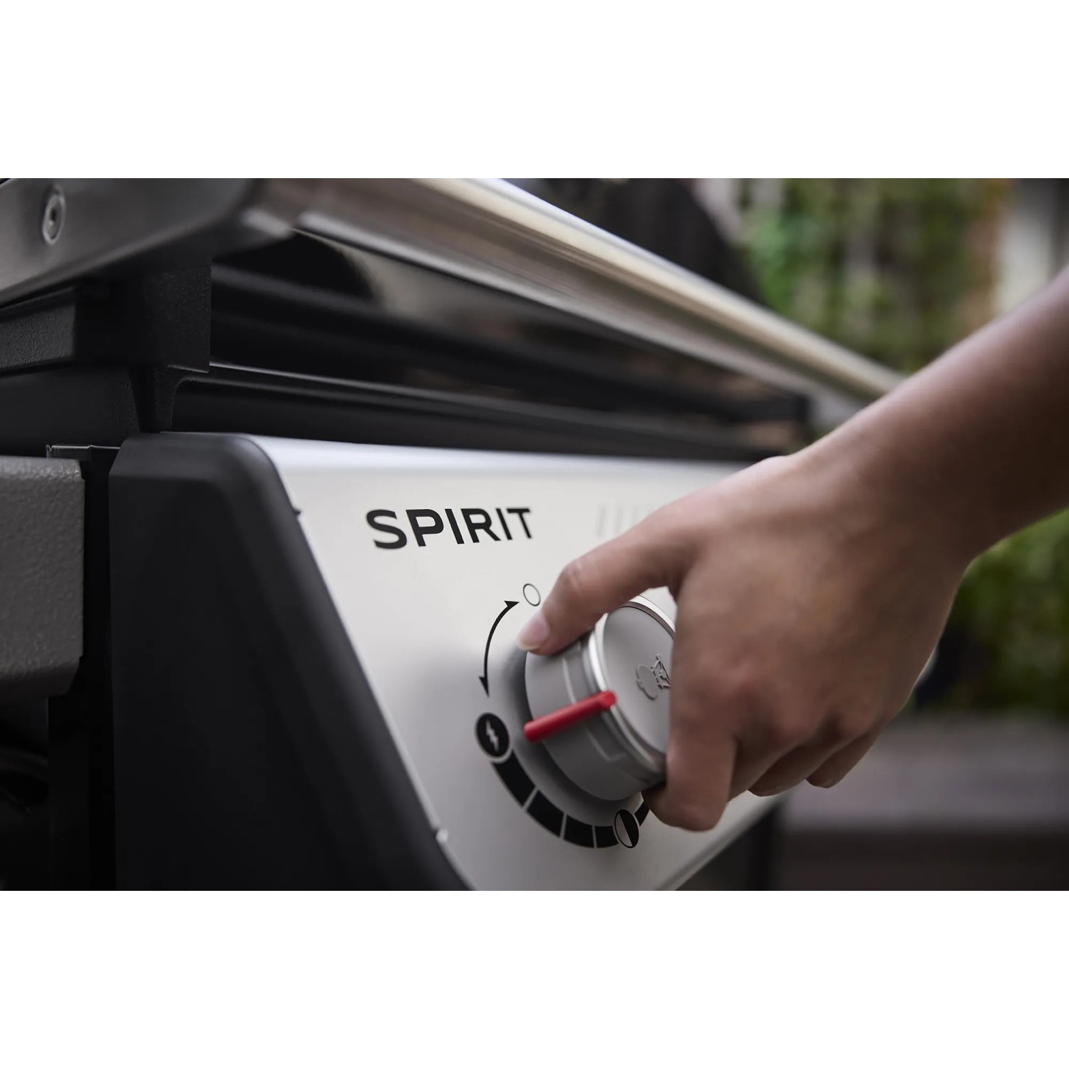 Nahaufnahme: Hand bedient Drehknopf am Weber Gasgrill E-210 Spirit, um die Hitze einzustellen.