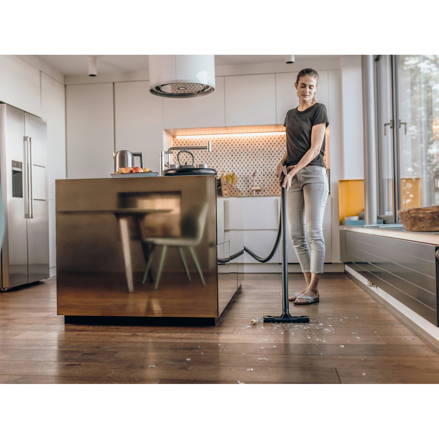 Frau saugt mit Kärcher WD 3 S V-17/4/20 Nass-/Trockensauger Holzboden in Küche.