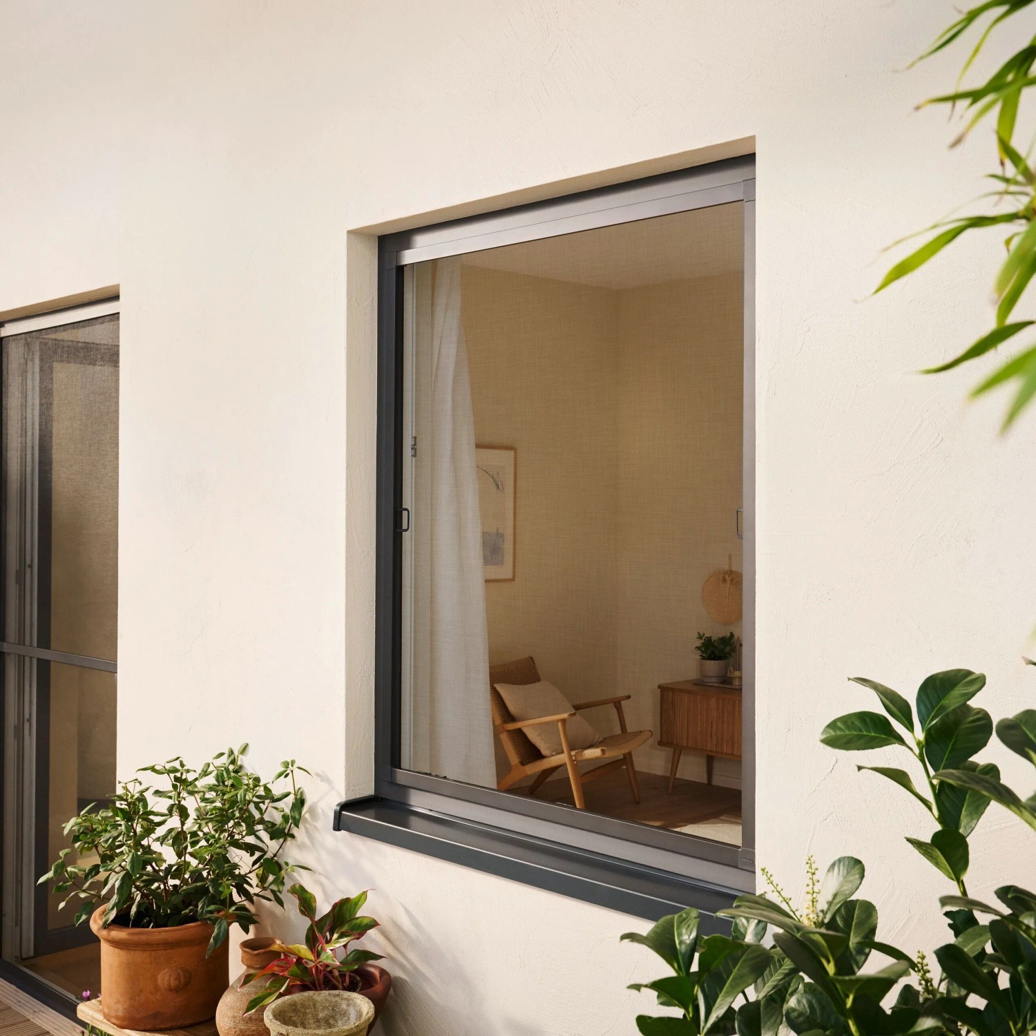 Anthrazitfarbenes tesa Fliegengitter Alu Comfort am Fenster, schützt vor Insekten.