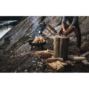 Mann spaltet Holz mit Fiskars Axt N12 am Lagerfeuer. Axt mit Hickory-Holz Griff.