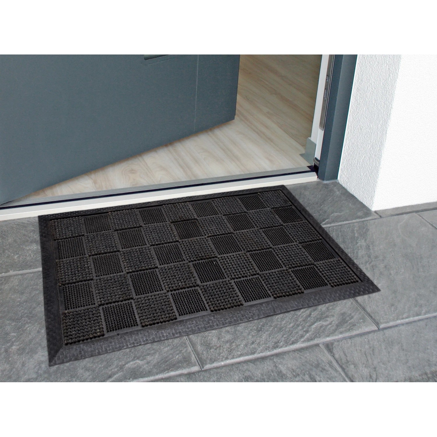 Graue OBI Gummimatte (40x60 cm) mit Noppen vor einer Tür. Fußmatte für den Außenbereich.