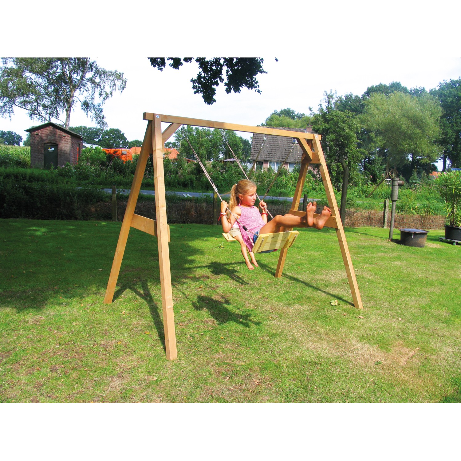 Braune Axi Doppelschaukel aus Holz mit Mädchen auf dem Schaukelsitz im Garten.