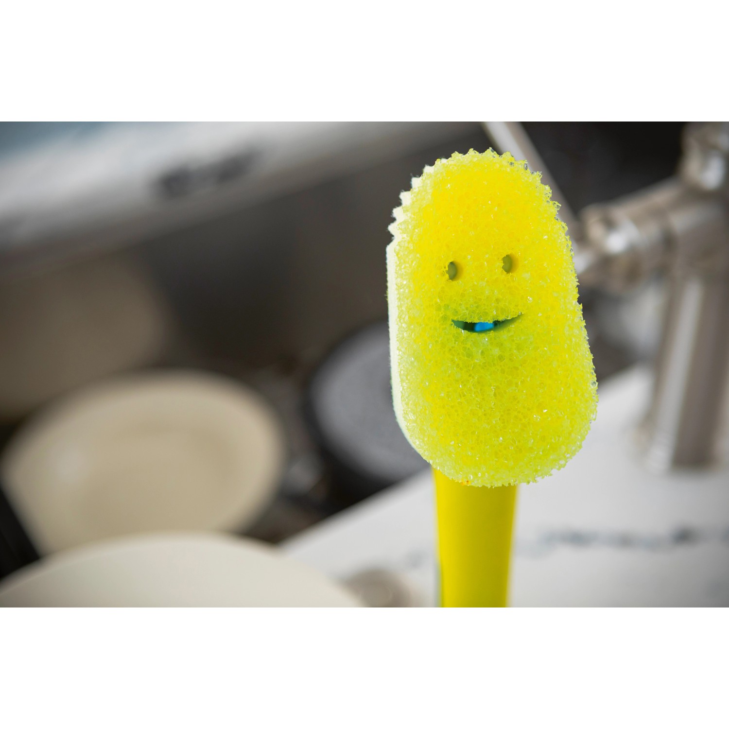 Gelbe Spülbürste Dish Daddy mit Schwamm und Gesicht im Spülbecken.