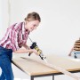 Frau trägt Soudal Fix All Turbo Kleber auf Holzleiste auf.