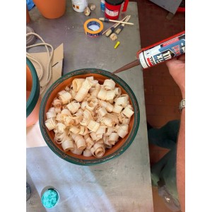 Hand hält braune Soudal Fix All Flexi Dichtstoff-Kartusche über Holzspänen. Vielseitiger Kleber für Silikon & Acryl.