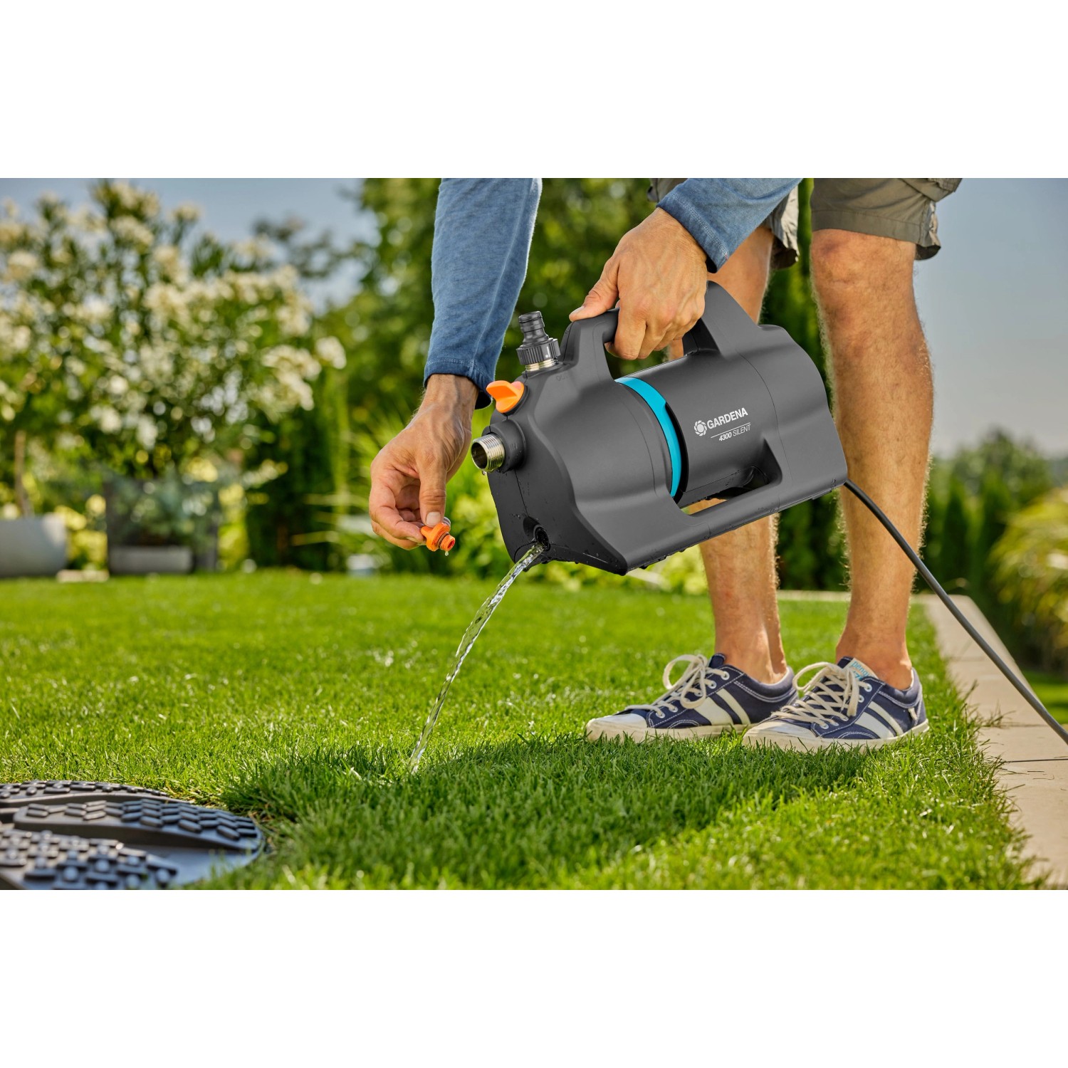 Gardena Gartenpumpe 4300 Silent in Aktion: Graue Pumpe mit blauem Akzent beim Wasserablassen im Garten.