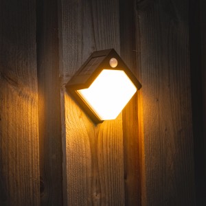 Leuchtende Solar-Wandleuchte Pretoria in Schwarz mit Sensor an Holzwand.
