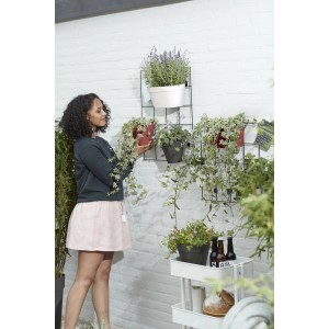Frau bepflanzt Wandgitter mit Elho Loft Urban Single Hängetopf Ø 15 cm, Farbe Weiß.