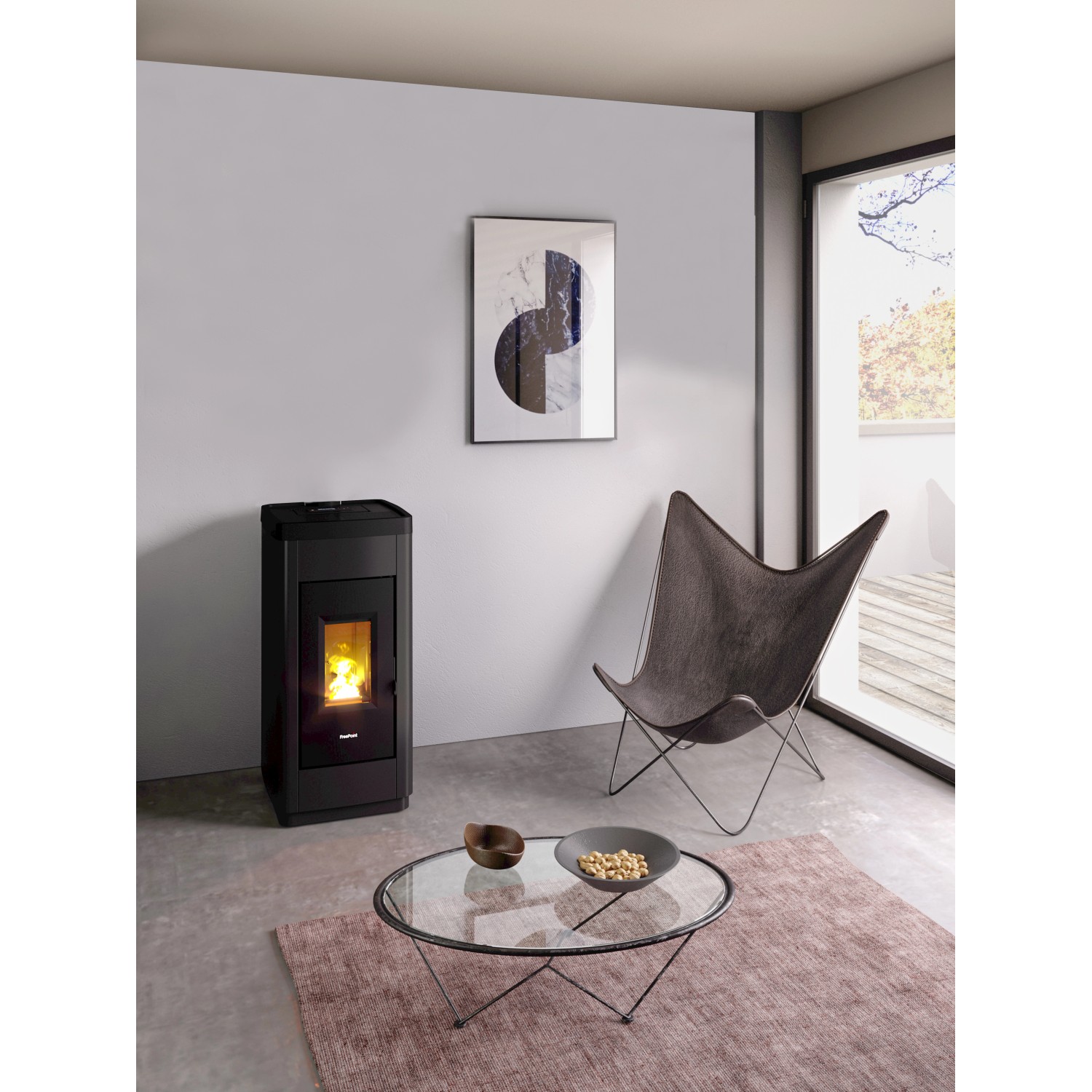 Schwarzer Freepoint Pelletofen LIFE 8,5 kW im Wohnraum mit Sessel und Tisch.