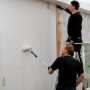 Zwei Handwerker verarbeiten eine imprägnierte Gipskartonplatte im Innenausbau mit Farbrollern.