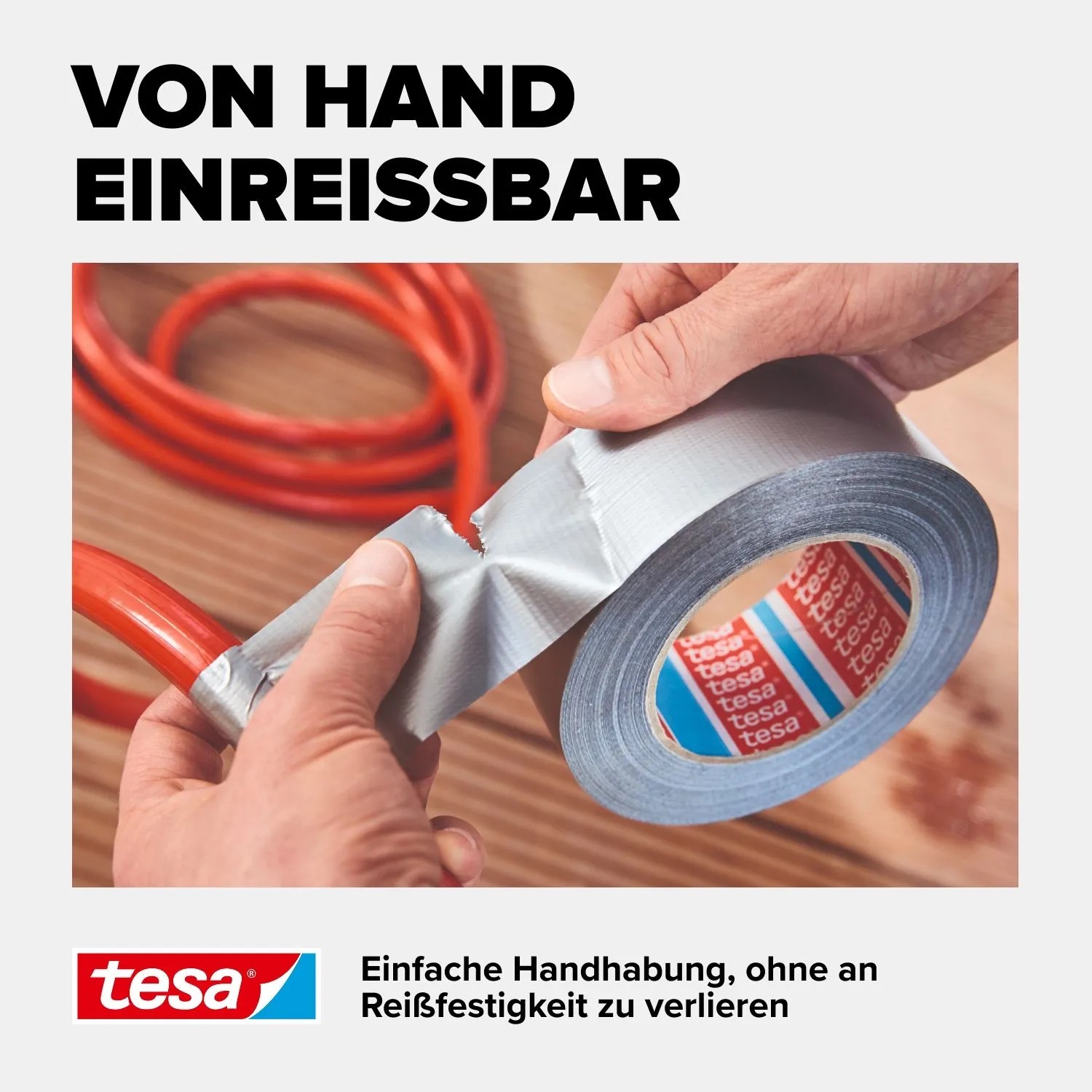 Hände reißen silbernes Tesa Extra Power Universal Klebeband zur Reparatur eines roten Kabels ab.