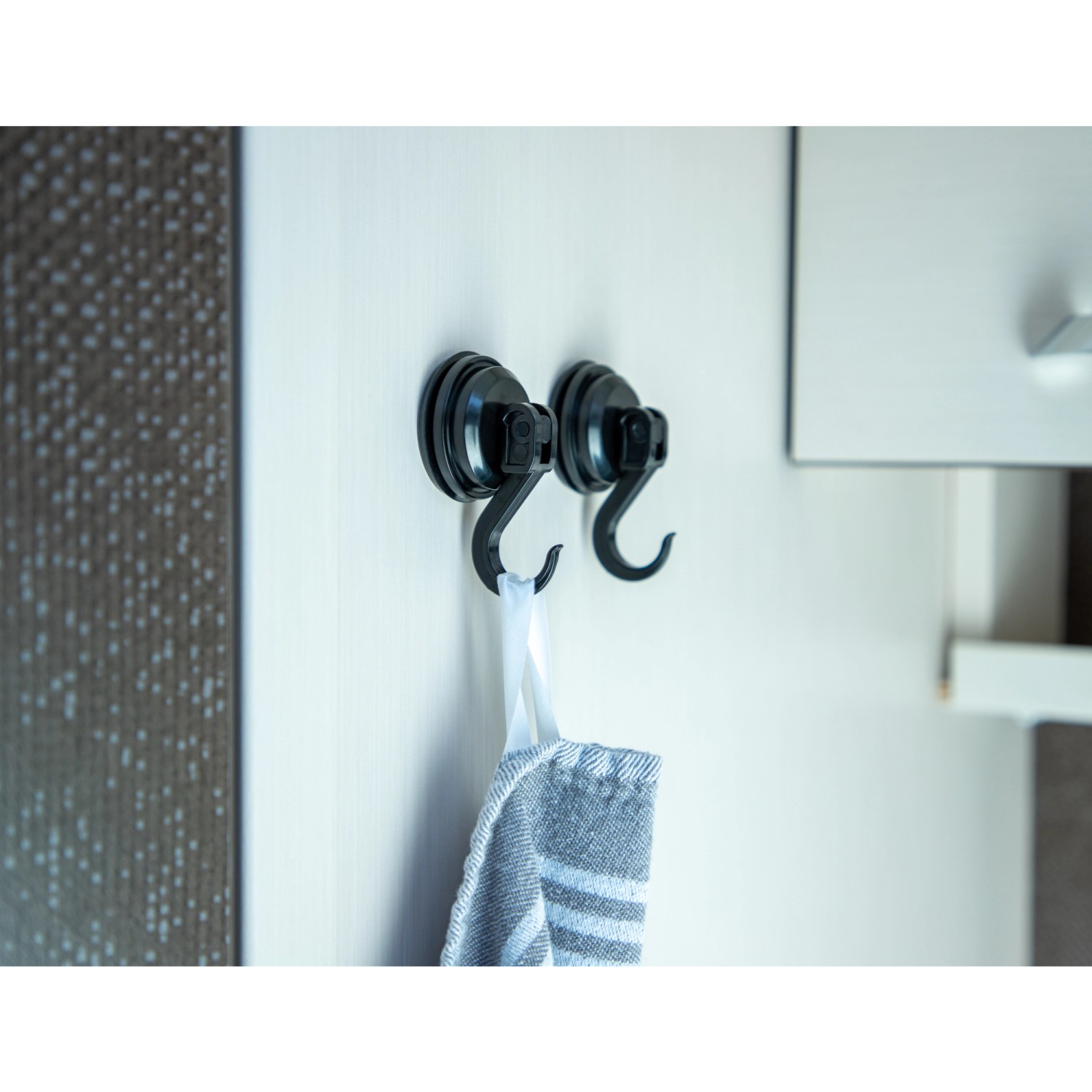 2 schwarze Cartrend Saughaken mit Handtuch an weißer Tür befestigt.