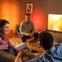 Philips Hue Signe Tischleuchte in Weiß im Wohnzimmer mit Personen.