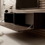 Selsey TV-Hängeboard Bisira 140 cm in Nussbaum-Holzoptik mit offenen Klapptüren, an einer Holzpaneelwand. Modernes Design, Stauraum.