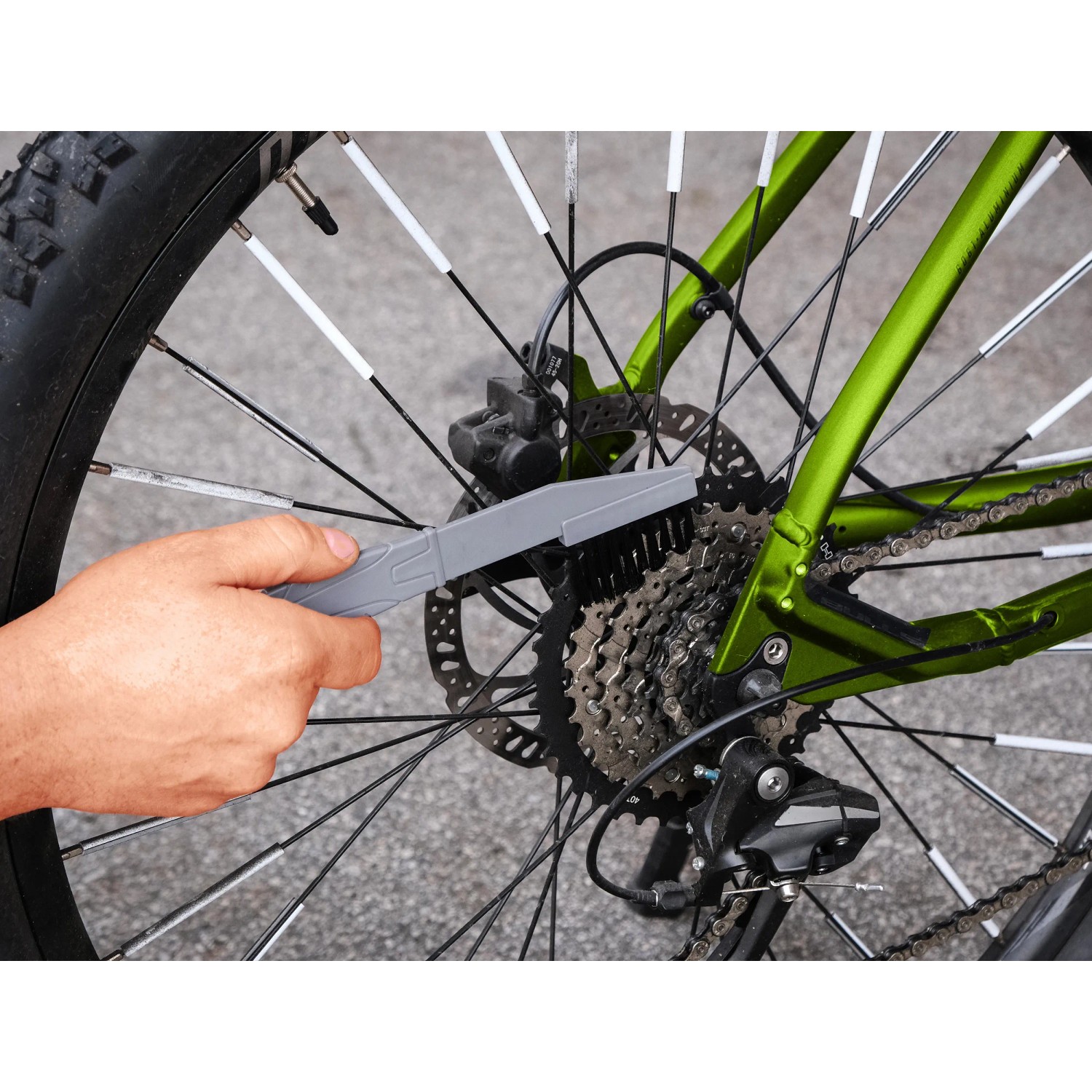 Fahrrad-Pflegeset: Hand reinigt mit Bürste den Zahnkranz eines Fahrrads.
