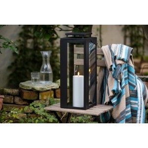 Schwarze FlowerPower LED-Laterne Lucido, 48,5 cm, mit Kerze auf einem Tisch im Garten.