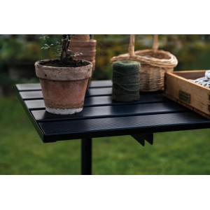Schwarzer, klappbarer Halls Lamellentisch 235x55cm mit Gartenzubehör auf der Tischfläche.