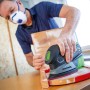 Mann schleift Holz mit LUX Akku-Multischleifer A-MS-20. Kabellose Schleifmaschine für Holz und Metall.