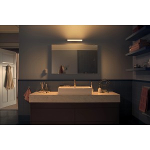 Philips Hue Adore Wandleuchte in Chrom über Spiegel im Bad, warmes Licht.