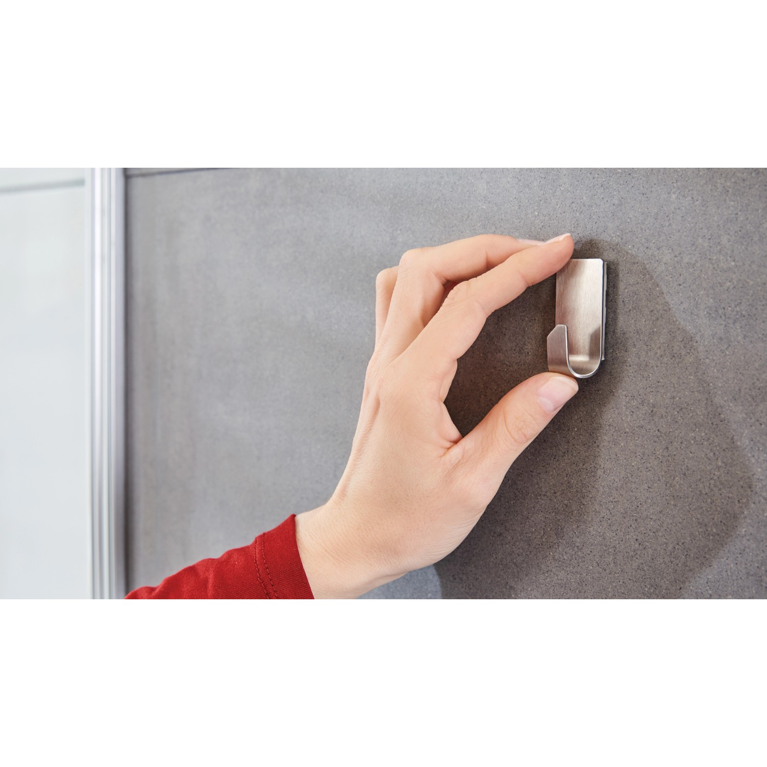 Hand befestigt Tesa Powerstrips Haken Waterproof Zoom Edelstahl an grauer Fliese.