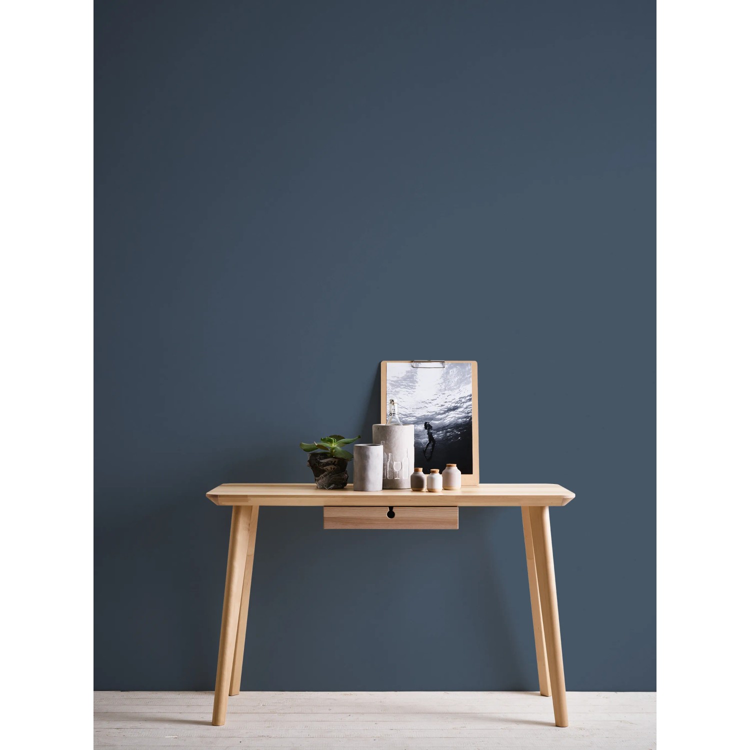 Michalsky Living Change Vliestapete Uni Blau an Wand hinter Tisch mit Deko.
