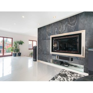 Wohnzimmer mit Wandverkleidung aus Steinfurnier Cali Gold 2.0 Naturstein, 60x120 cm.