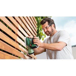 Mann schleift Holzzaun mit Bosch Akku-Exzenterschleifer EasyOrbit 18V-10. Schleifmaschine für Holz.