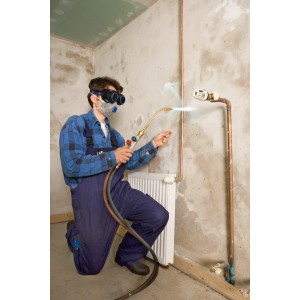 Handwerker mit LUX Feinstaubmaske und Schweißbrenner beim Löten eines Rohrs.