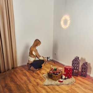Frau montiert Ständer für Kunsttanne Blavand 180 cm XL, geschmückt mit Deko im Wohnzimmer.