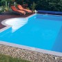 Rechteckiger Styropor Pool mit Römertreppe, Holzdeck und zwei Liegen im Garten.