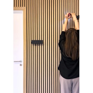 Montage einer schwarzen Denpanels Abschlussleiste Eiche geölt an einer Paneelwand.