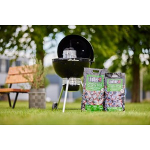 Weber Kokosbriketts 4 kg mit Grill im Hintergrund. Grillanzünder für lange Grilldauer.