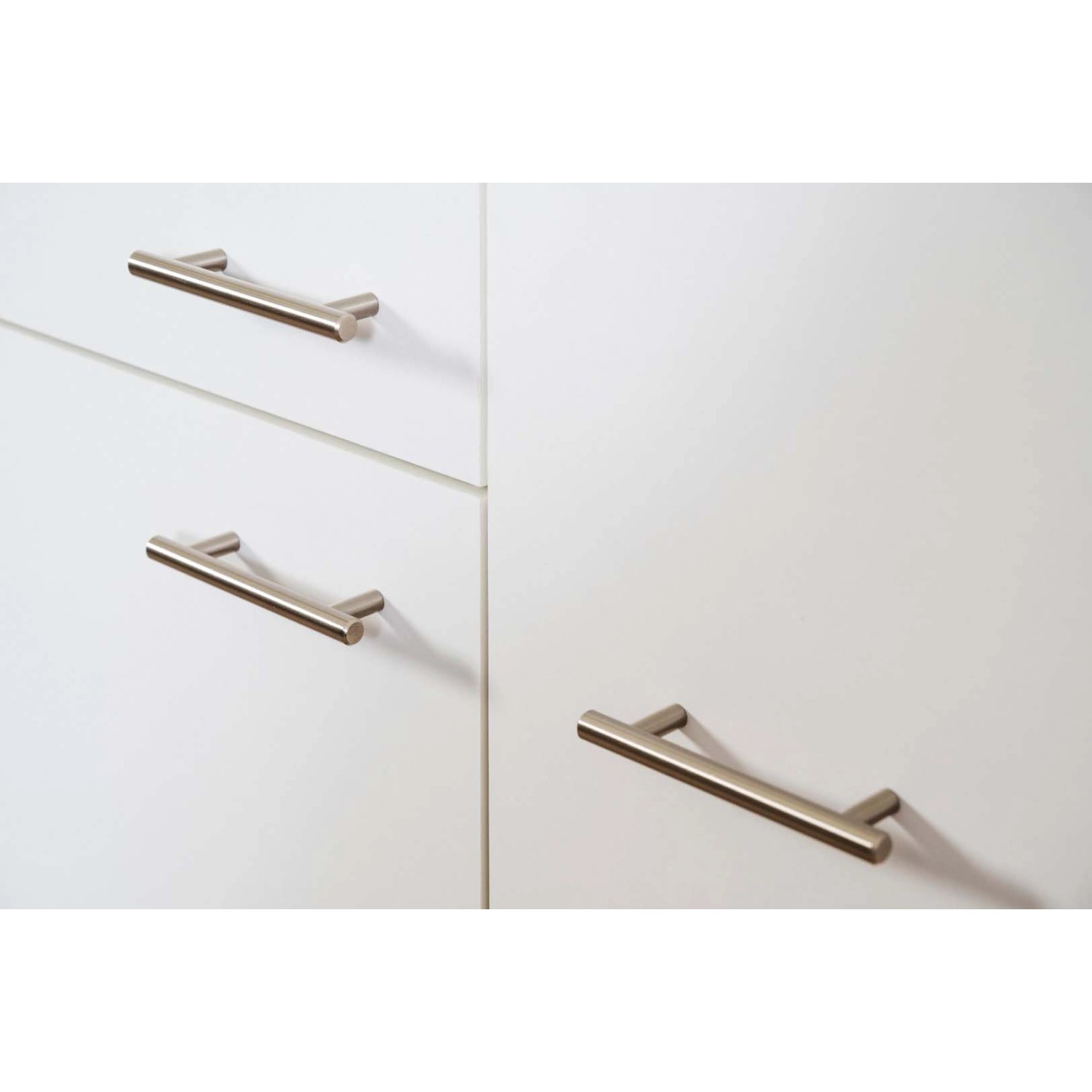 Detailaufnahme: Weiße Küchenfronten der Respekta Küchenzeile mit Edelstahlgriffen.