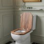 Sinobath MDF WC-Sitz eckig in Holzoptik mit Absenkautomatik auf weißer Toilette im Bad.